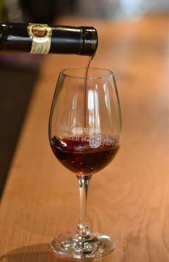 Rotwein wird in ein Glas eingeschenkt.